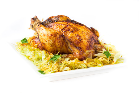 Grilled whole chicken with golden crust and garnish of stewed cabbage, isolated on white backgroundの写真素材