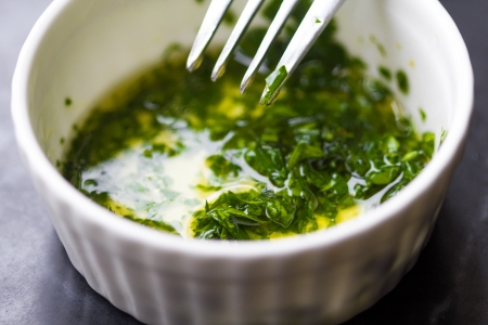 Fresh salad dressing of olive oil, lemon juice and herb parsley in white cupの写真素材