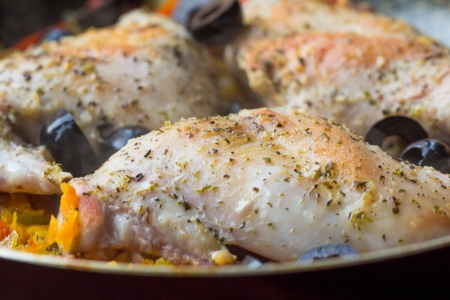 Fried ruddy leg of rabbit with vegetables, olives and herbs on frying pan, cooking homemade dinnerの写真素材