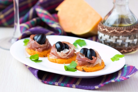 Canape appetizer of pumpkin, jamon ham, black olives, cheese, gourmet Italian mealの写真素材