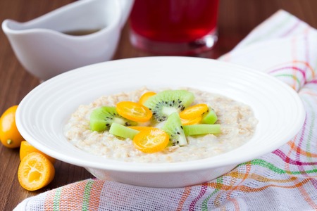Oat porridge with fruit, orange, cumquat, kiwi, maple syrup, delicious, healthy breakfastの写真素材