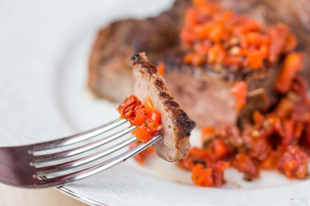 Grilled beef steak with salsa sauce made from sun-dried tomatoes, red peppers and green zucchini salad with spinach, delicious dinnerの写真素材