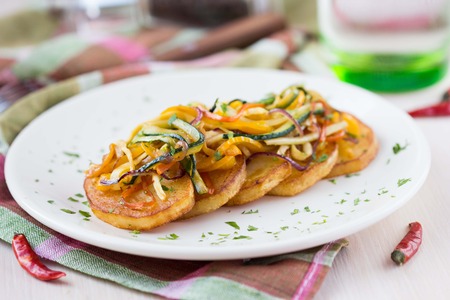 Fried slices of potato with finely chopped sticks vegetables, lean, vegetarian dish for dinnerの写真素材