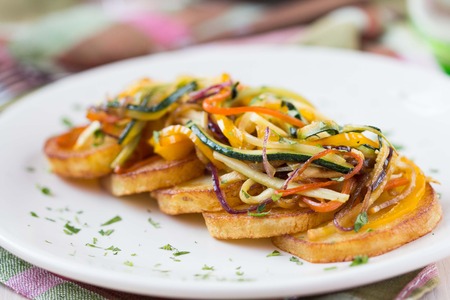 Fried slices of potato with finely chopped sticks vegetables, lean, vegetarian dish for dinnerの写真素材