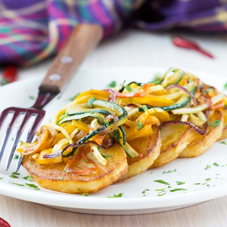 Fried slices of potato with finely chopped sticks vegetables, lean, vegetarian dish for dinnerの写真素材