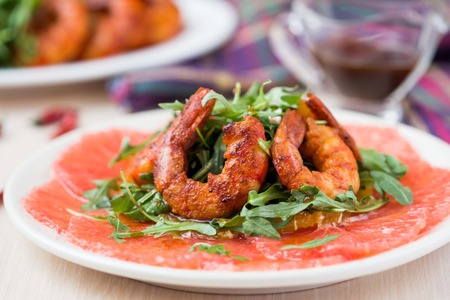 Carpaccio of grapefruit with rucola, arugula salad and spicy fried prawns, shrimpの写真素材