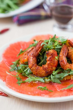 Carpaccio of grapefruit with rucola, arugula salad and spicy fried prawns, shrimpの写真素材