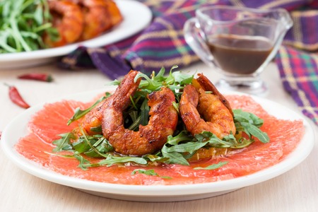 Carpaccio of grapefruit with rucola, arugula salad and spicy fried prawns, shrimpの写真素材