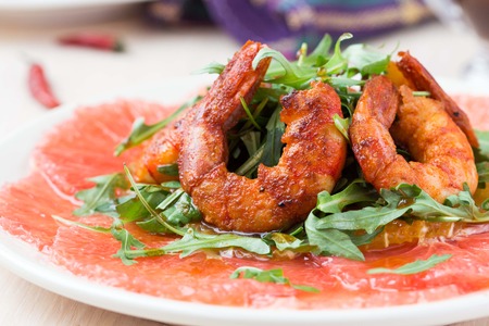 Carpaccio of grapefruit with rucola, arugula salad and spicy fried prawns, shrimpの写真素材