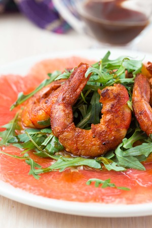 Carpaccio of grapefruit with rucola, arugula salad and spicy fried prawns, shrimpの写真素材