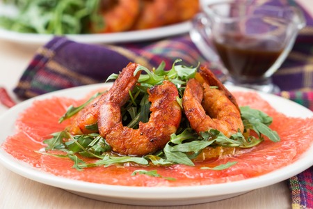 Carpaccio of grapefruit with rucola, arugula salad and spicy fried prawns, shrimpの写真素材
