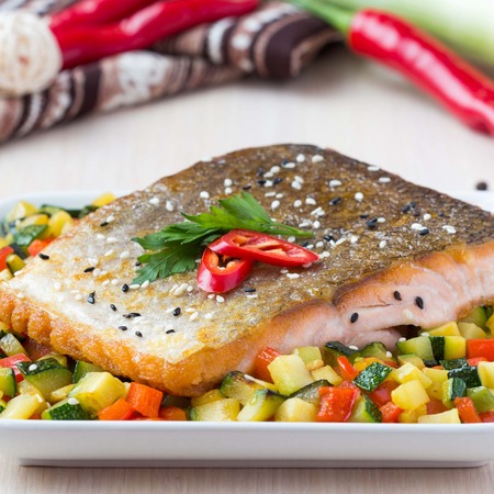 Fried fillet of red fish salmon with crispy skin, roasted vegetables, zucchini, pepper, beautiful dishの写真素材