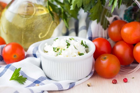 White soft cheese, feta, goat in bowl with tomatoes, parsley, olive oilの写真素材