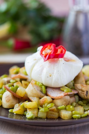 Hot appetizer salad with potatoes, ham, green peas, mushrooms, poached egg, tasty dishの写真素材