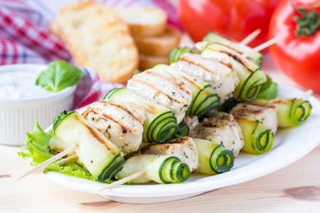 Grilled chicken filet kebab, shashlik on skewers with rolled zucchini, tasty picnic dishの写真素材