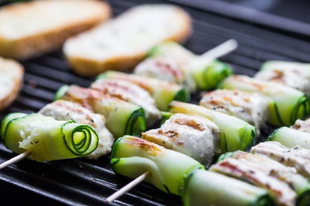 Cooking grilled chicken kebab, shashlik on skewers with rolled zucchini, toast, tasty dishの写真素材