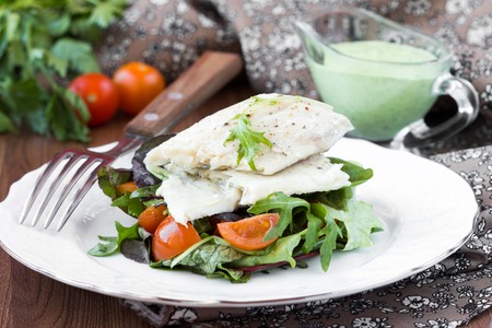 Fried white fish fillet with salad of lettuce, arugula, greens, tomatoes, green sauce with pea,...