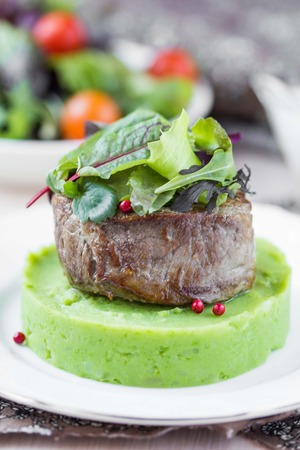 Grilled beef steak, green mashed potatoes with peas, herbs, beautiful presentation in restaurantの写真素材