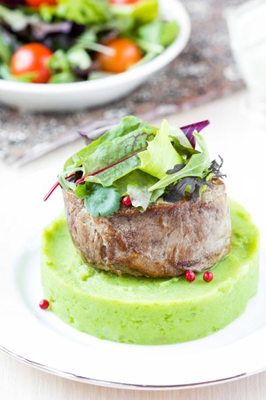 Grilled beef steak, green mashed potatoes with peas, herbs, beautiful presentation in restaurantの写真素材