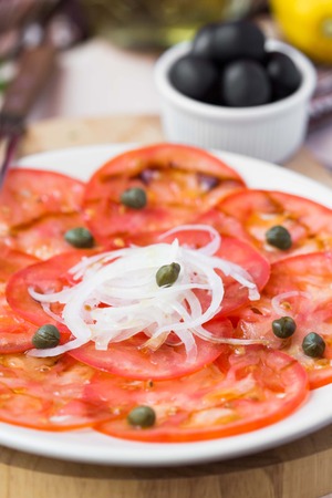 Fresh healthy tomato carpaccio with capers, balsamic vinegar, olive oil, tasty summer appetizerの写真素材