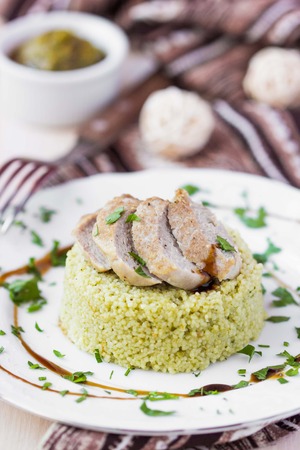 Couscous with pesto sauce, fried sliced pork, tasty dish, beautiful presentationの写真素材