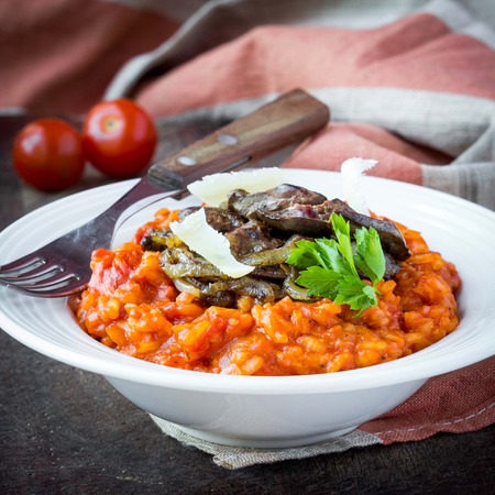 Tomato risotto, red rice with fried chicken liver, onions, homemade Italian dishの写真素材