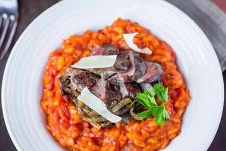 Tomato risotto, red rice with fried chicken liver, onions, homemade Italian dishの写真素材