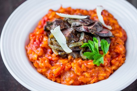 Tomato risotto, red rice with fried chicken liver, onions, homemade Italian dishの写真素材