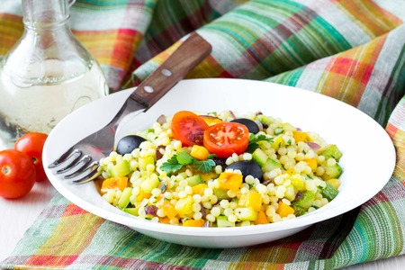 Israeli couscous ptitim with vegetables, zucchini, peppers, tomatoes, parsley, vegetarian diet healthy summer dishの写真素材