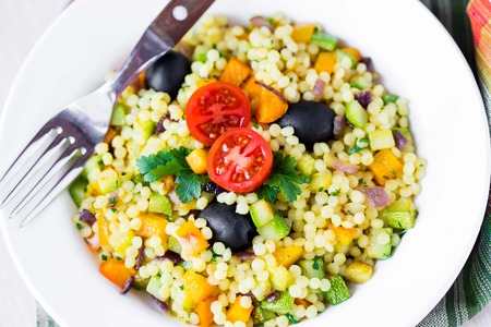 Israeli couscous ptitim with vegetables, zucchini, peppers, tomatoes, parsley, vegetarian diet healthy summer dishの写真素材