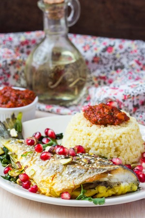 Whole roasted Dorado fish with couscous, pomegranate, herbs and tomato sauce, Arabic dishの写真素材