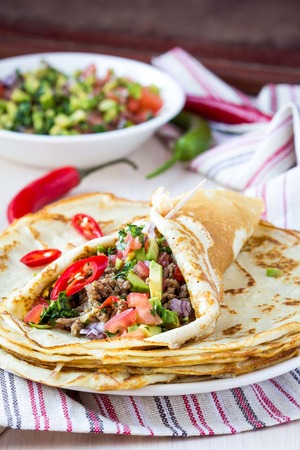 Pancakes stuffed with meat, avocado, tomatoes, onions, Mexican taste, Russian Shroveの写真素材