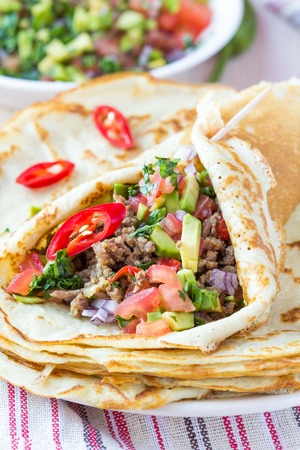 Pancakes stuffed with meat, avocado, tomatoes, onions, Mexican taste, Russian Shroveの写真素材