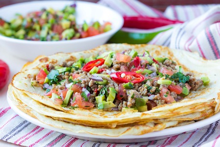 Pancakes stuffed with meat, avocado, tomatoes, onions, Mexican taste, Russian Shroveの写真素材