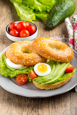 Bagel sandwich with avocado, boiled egg, green salad lettuce, delicious breakfastの写真素材