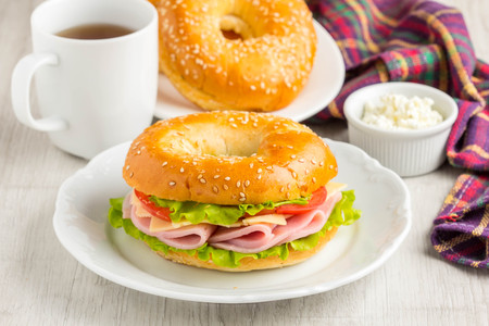 Bagel sandwich with ham, cheese, tomato, green salad lettuce, teaの写真素材