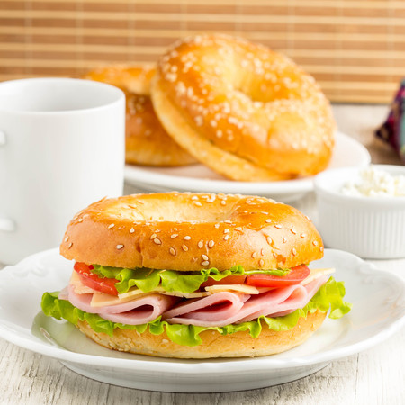 Bagel sandwich with ham, cheese, tomato, green salad lettuce, teaの写真素材