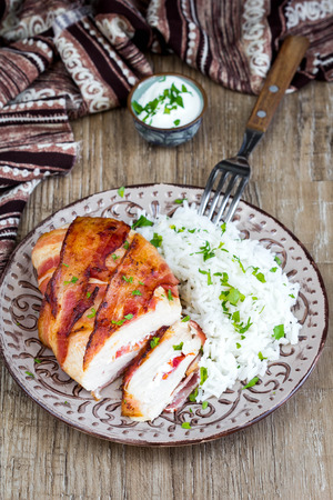 Chicken wrapped in bacon stuffed with soft cheese with rice, tasty homemade dish, beautiful foodの写真素材