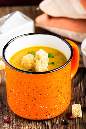 Orange cream soup in Ñup with croutons, carrot, pumpkin, delicious hot soup, homemade dinner in rustic styleの写真素材