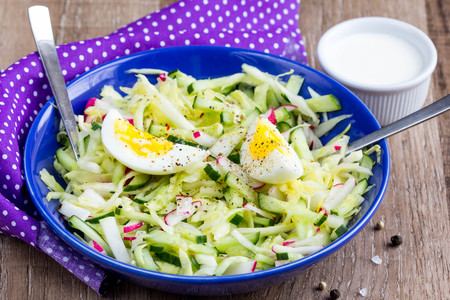 Fresh salad with cabbage, cucumber, radish and egg, healthy spring dish in rustic style and bright presentationの写真素材