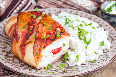 Chicken wrapped in bacon stuffed with soft cheese with rice, tasty homemade dish, beautiful foodの写真素材