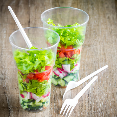Fresh vegetable salad in plastic disposable glass for picnic, take to work, healthy diet, delicious foodの写真素材