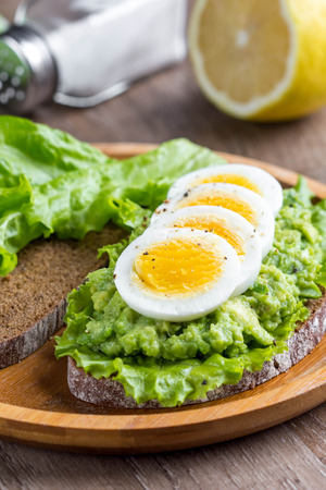 Sandwich with bread, mashed avocado, sliced eggs, green salad, delicious breakfast, healthy foodの写真素材