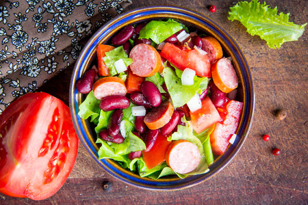 Salad with beans, tomatoes, onion, smoked sausage, lettuce, tasty dish in traditional rustic styleの写真素材
