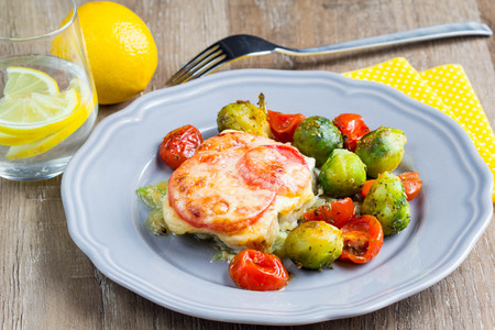 Fish baked with cheese and tomatoes, Brussels sprouts and cherry tomatoes, delicious dish, healthy foodの写真素材