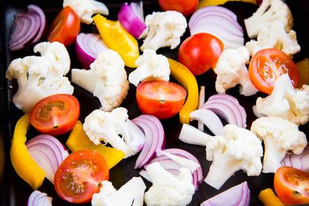 Fresh vegetables on baking sheet before baking, cauliflower, onions, tomatoes, pepper, paprikaの写真素材