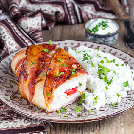Chicken wrapped in bacon stuffed with soft cheese with rice, tasty homemade dishの写真素材