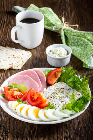 Diet breakfast, ham, tomatoes, boiled egg, crisp bread, soft cheese, green salad, coffee, tasty foodの写真素材