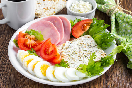 Diet breakfast, ham, tomatoes, boiled egg, crisp bread, soft cheese, green salad, coffee, tasty foodの写真素材