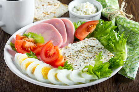 Diet breakfast, ham, tomatoes, boiled egg, crisp bread, soft cheese, green salad, coffee, tasty foodの写真素材